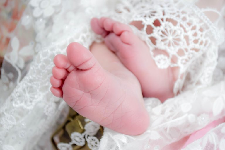 piedini di neonato avvolti in tunica di pizzo