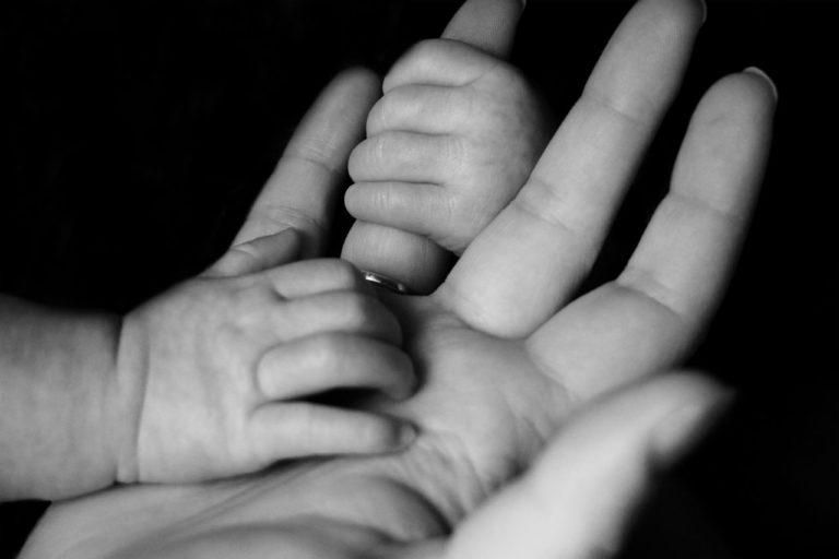 mano di adulto con manine di neonato