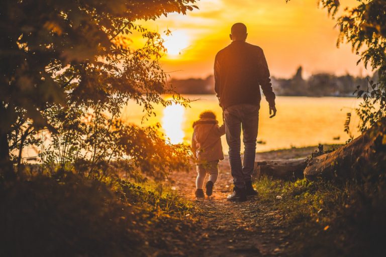 padre con figlia piccola passeggiano al tramonto - festa del papà